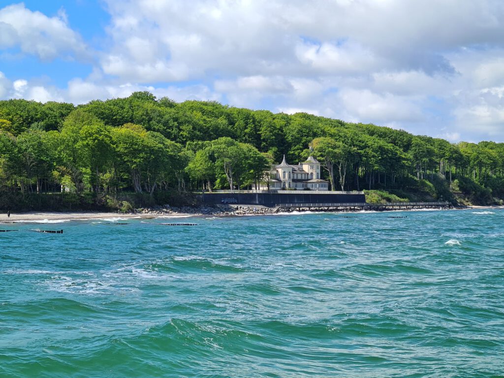 Meer mit Wald und Schlossähnlichem Gebäude im Hintergrund